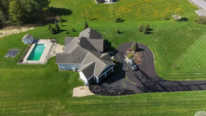 Aerial view of a residence, lawn, swimming pool and surrounding trees.