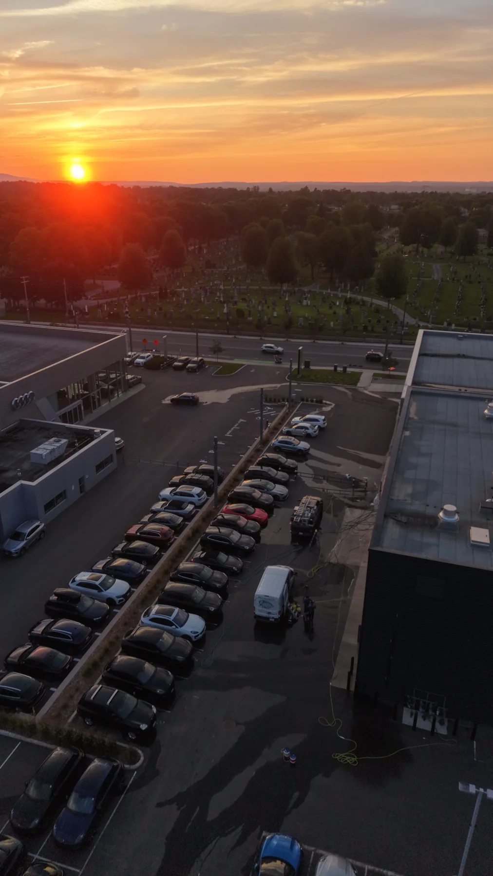 Warm sunset above a commercial area and surrounding trees.