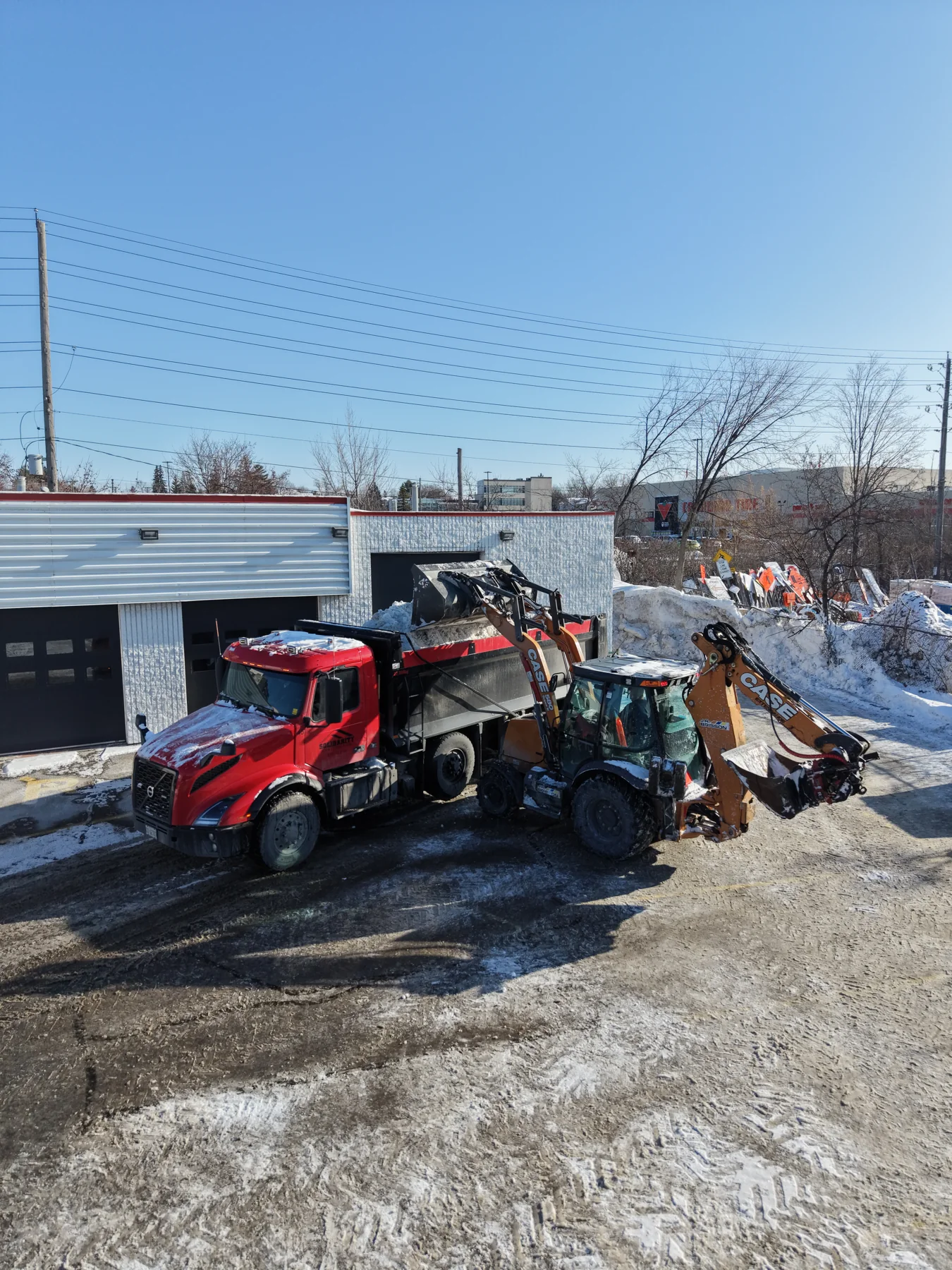 Winter project scene with a truck and equipment beside a commercial building.